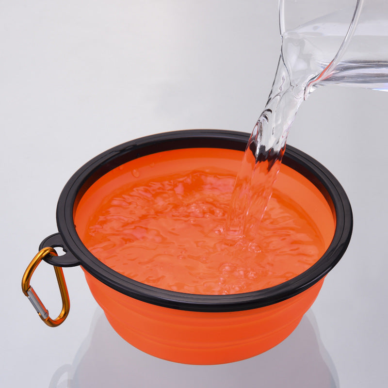 Wasser wird in einen faltbaren Reisenapf in Orange gegossen, kompakter Trinknapf für Hunde unterwegs